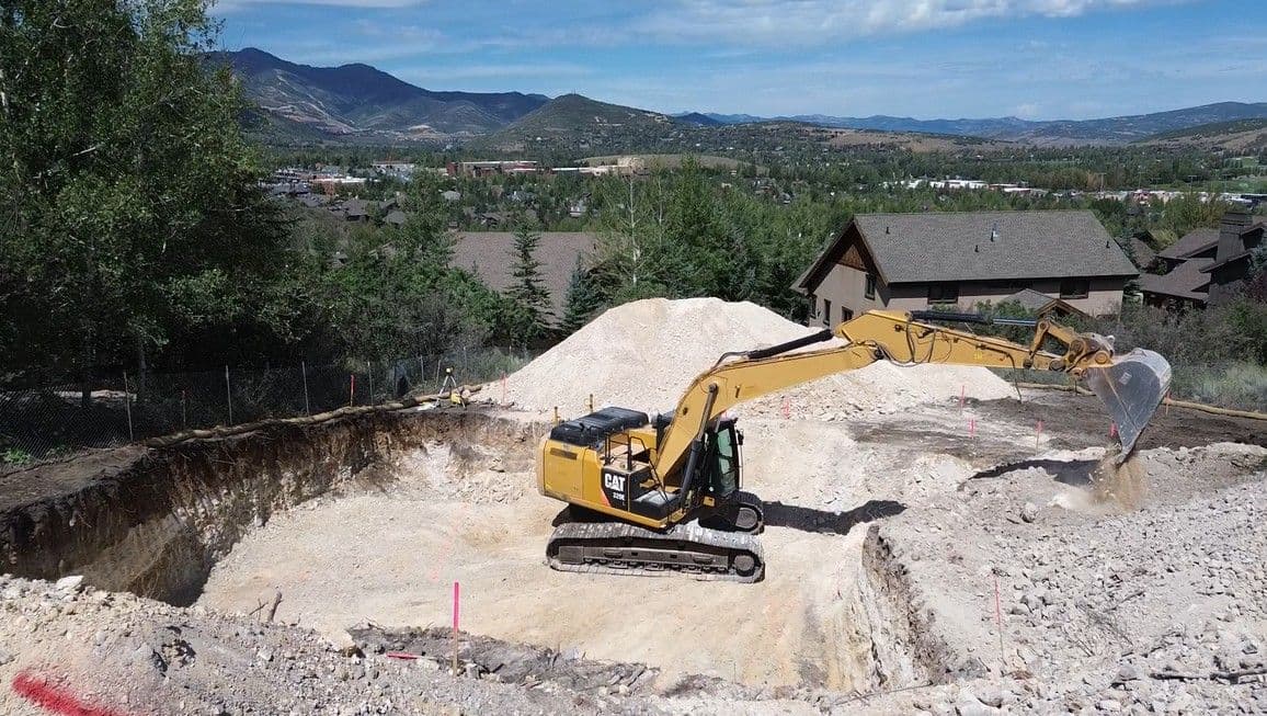 CAT excavator opening a building excavation above Park City